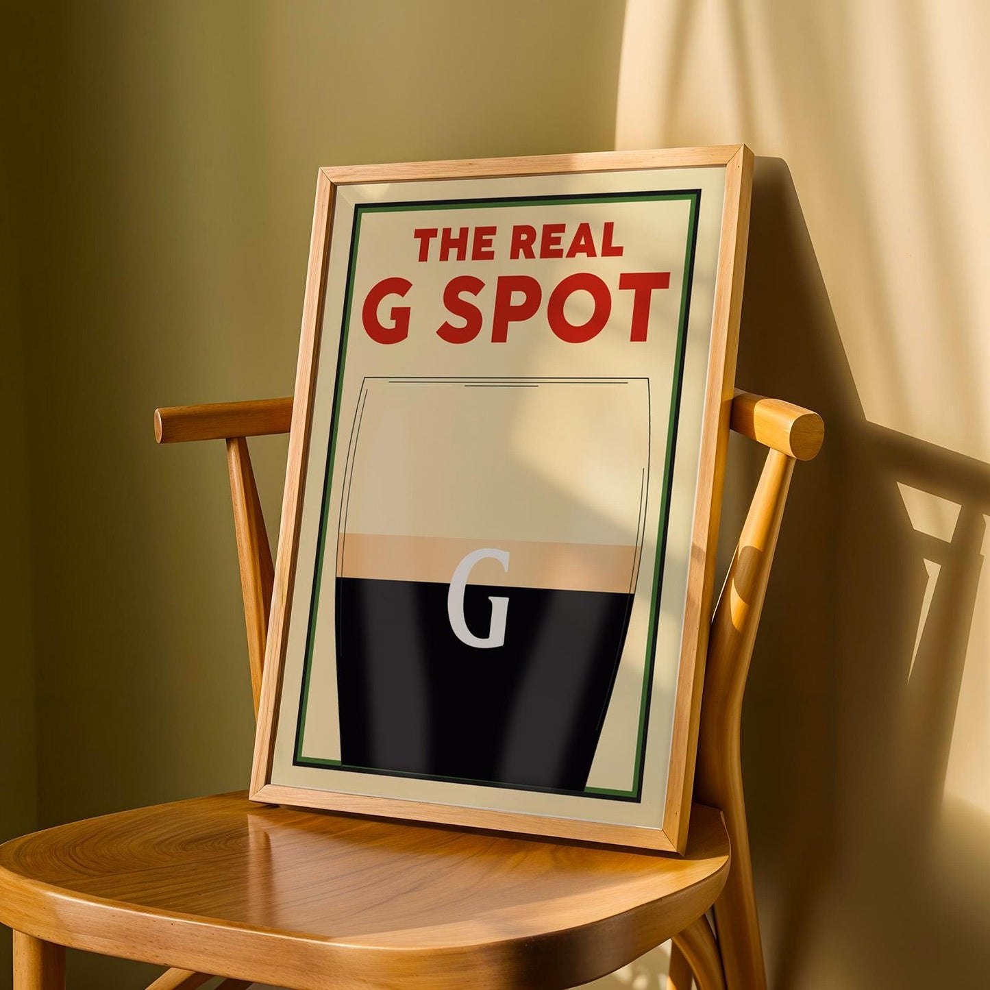 Beer-themed wall poster with witty G spot reference and pint glass design, leaning on a wooden chair.