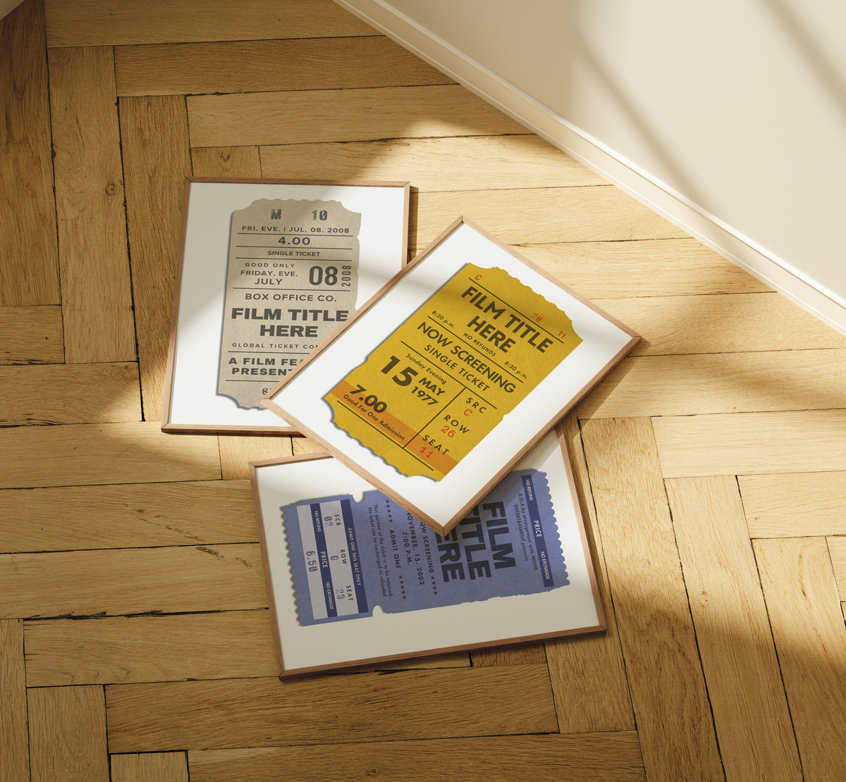 Three framed vintage-style movie ticket art prints arranged on a light wood herringbone floor in warm sunlight.