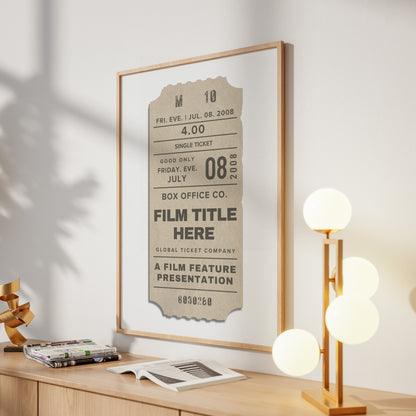 A framed vintage-style film ticket poster hangs on a light wall above a wooden console table. The print has a beige ticket design with black text and a thin light wood frame.