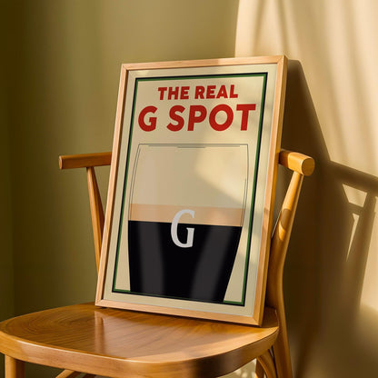 Beer-themed wall poster with witty G spot reference and pint glass design, leaning on a wooden chair.