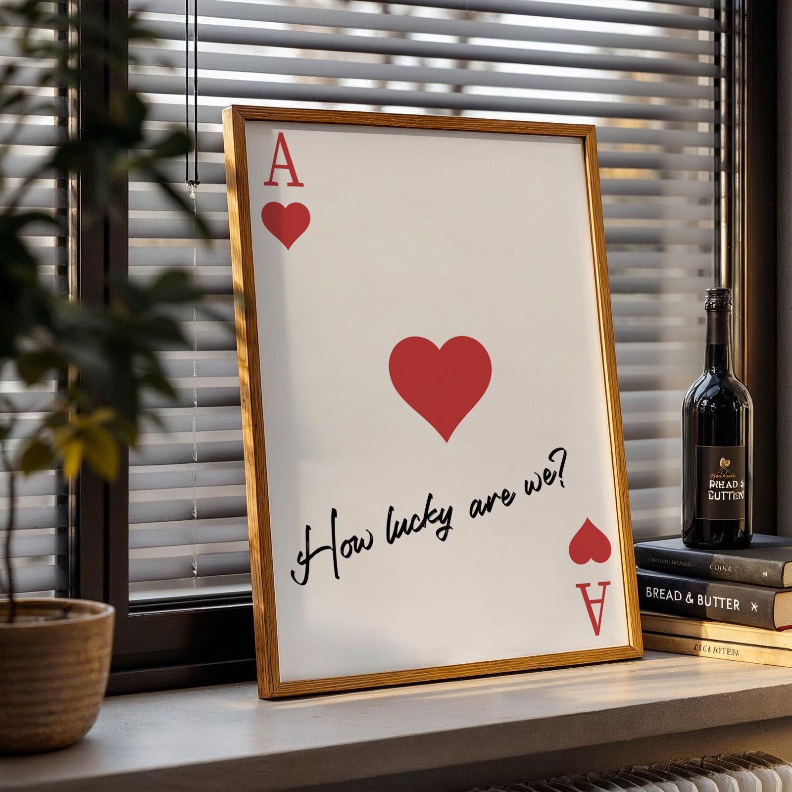 Framed ace of hearts card print with “How lucky are we?” text, leaning on counter.