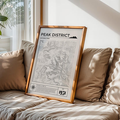 Framed Peak District map art leaning in living room, perfect gift for hiking and nature lovers.
