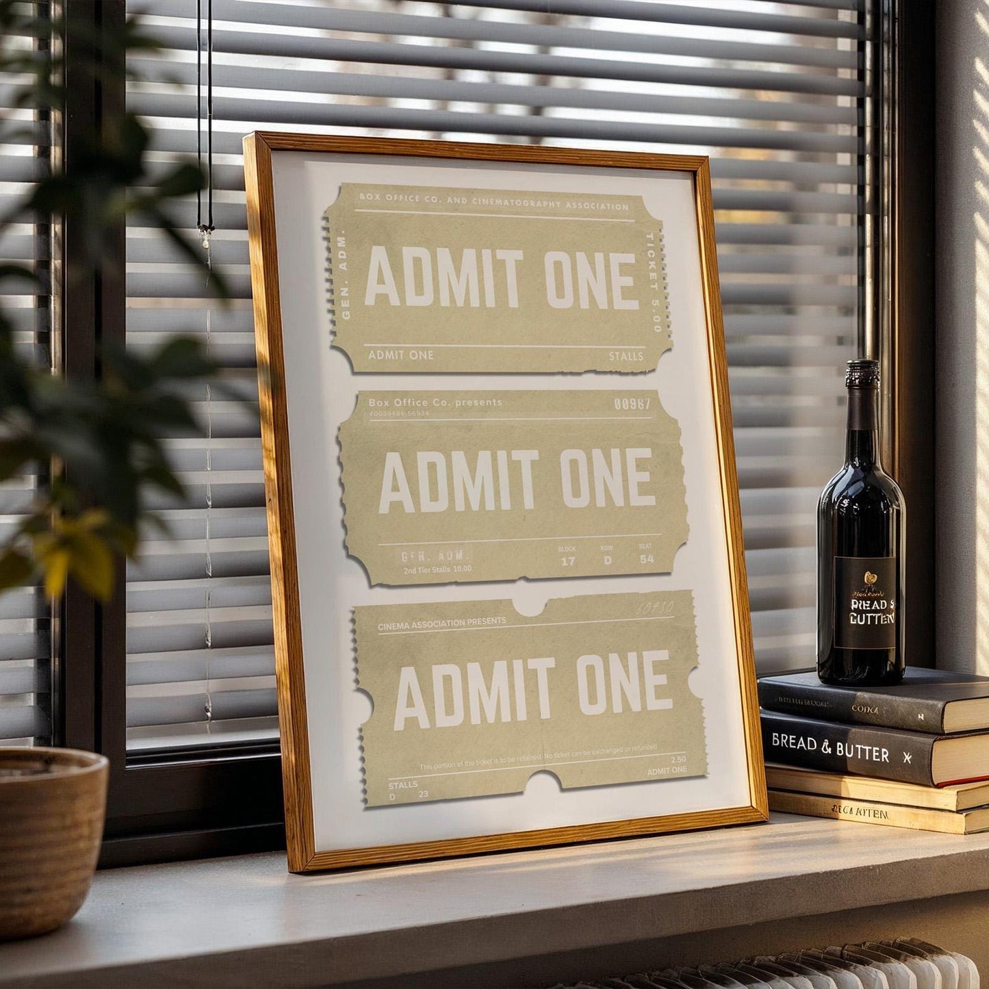 a beige neutral coloured print of a stub saying admit one. framed leaning on a window sill