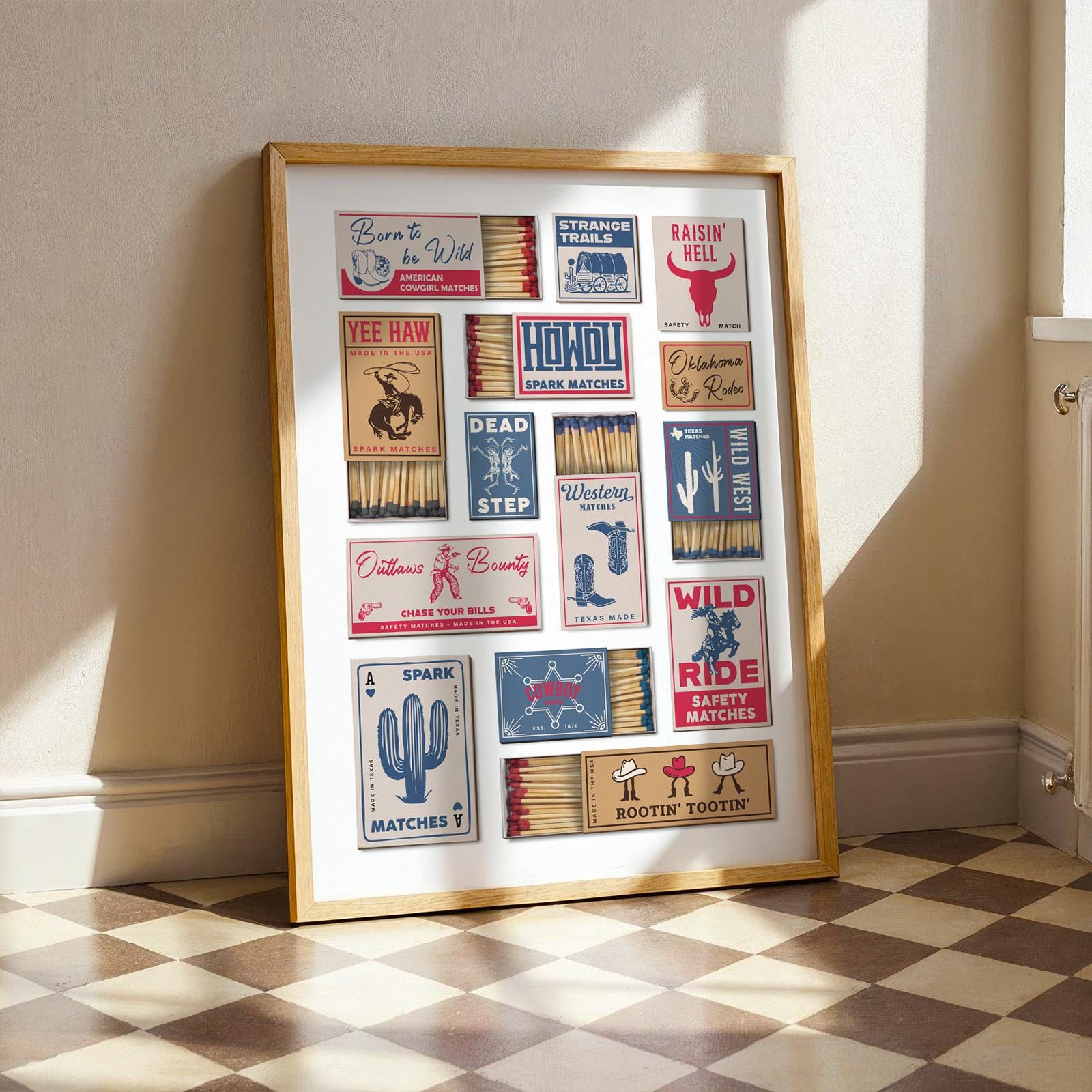 A print in a frame displaying a collection of matchbook designs with cowboy-themed imagery and text. The designs feature phrases such as "Rootin' Tootin'," alongside illustrations of cowgirls and landscapes. The frame is a light wood colour.