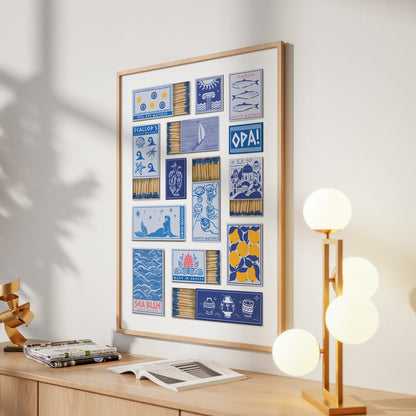 A print in a frame displaying a collection of matchbook designs. The designs include images of fish, a sailboat and the word "OPA!". The frame is light brown, and the print is on a white wall.
