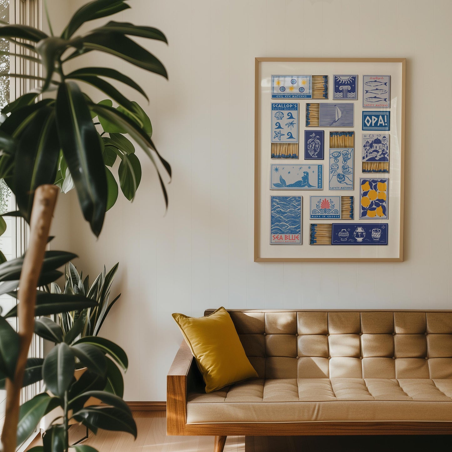 A greek inspired poster with a collage of illustrated matchbox designs. The artwork includes text. The print is displayed above a mid-century modern style sofa with a yellow cushion.