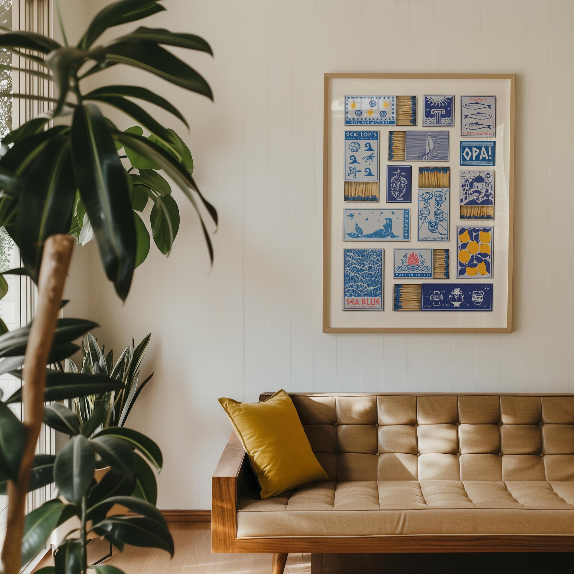 A greek inspired poster with a collage of illustrated matchbox designs. The artwork includes text. The print is displayed above a mid-century modern style sofa with a yellow cushion.