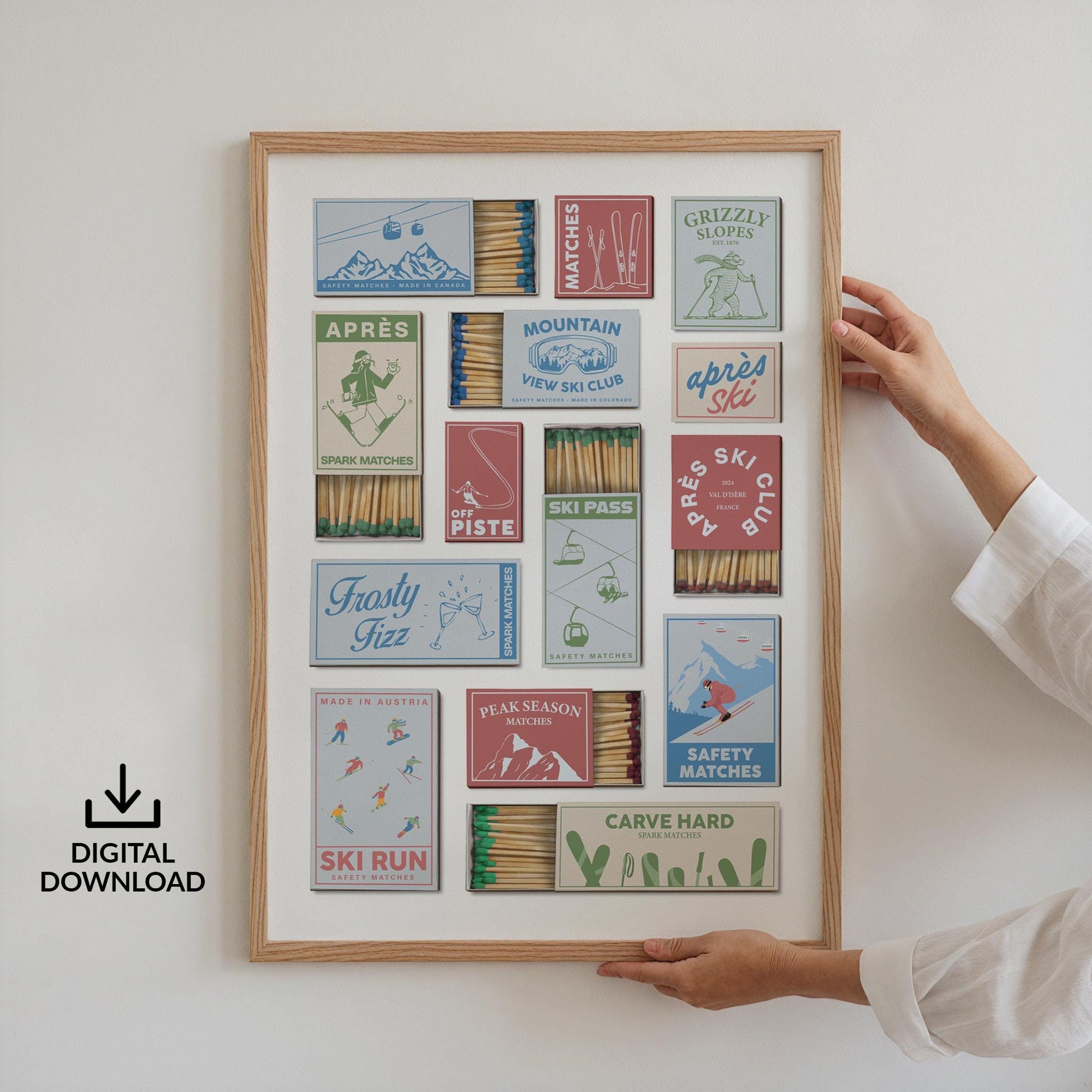 A framed print displaying a printable design of a collection of matchbox designs with ski-related imagery and text. The matchboxes are in blue, red, and green, with phrases such as "Après Ski," "Ski Run," and "Carve Hard." The print is held by a person.