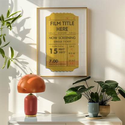 A framed poster with a yellow ticket design, displaying the film title chosen. The poster is displayed in a room with a lamp and plant on a shelf.