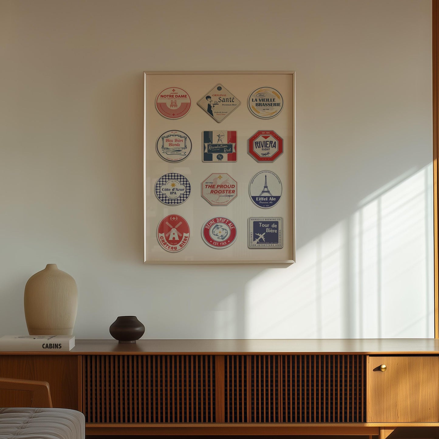 a stylish framed travel themed print on the wall above a brown tv unit with some vases on it. The poster shows various French themed beer mats in blues, red and white.