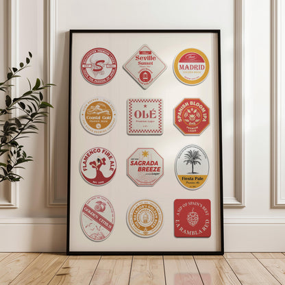 a white panelled wall with a plant to the left and a black framed spain travel art piece leaning on the wall. Retro beer mats with spanish themes are on the print in colours of red, yellow and orange.