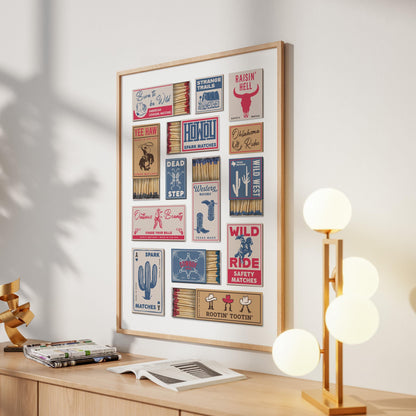 A framed masculine print displaying retro matchbox designs with a Southern theme. The matchbooks feature graphics and text such as "Dead Step" and "Raisin' Hell." The artwork is mounted on a wall above a wooden cabinet.