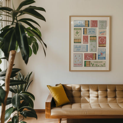 A stylish art piece displaying vintage matchbox designs with skiing resort themes. The matchboxes feature colourful illustrations and text, including "Frosty Fizz". The print hangs above a mid-century modern sofa with a yellow cushion.