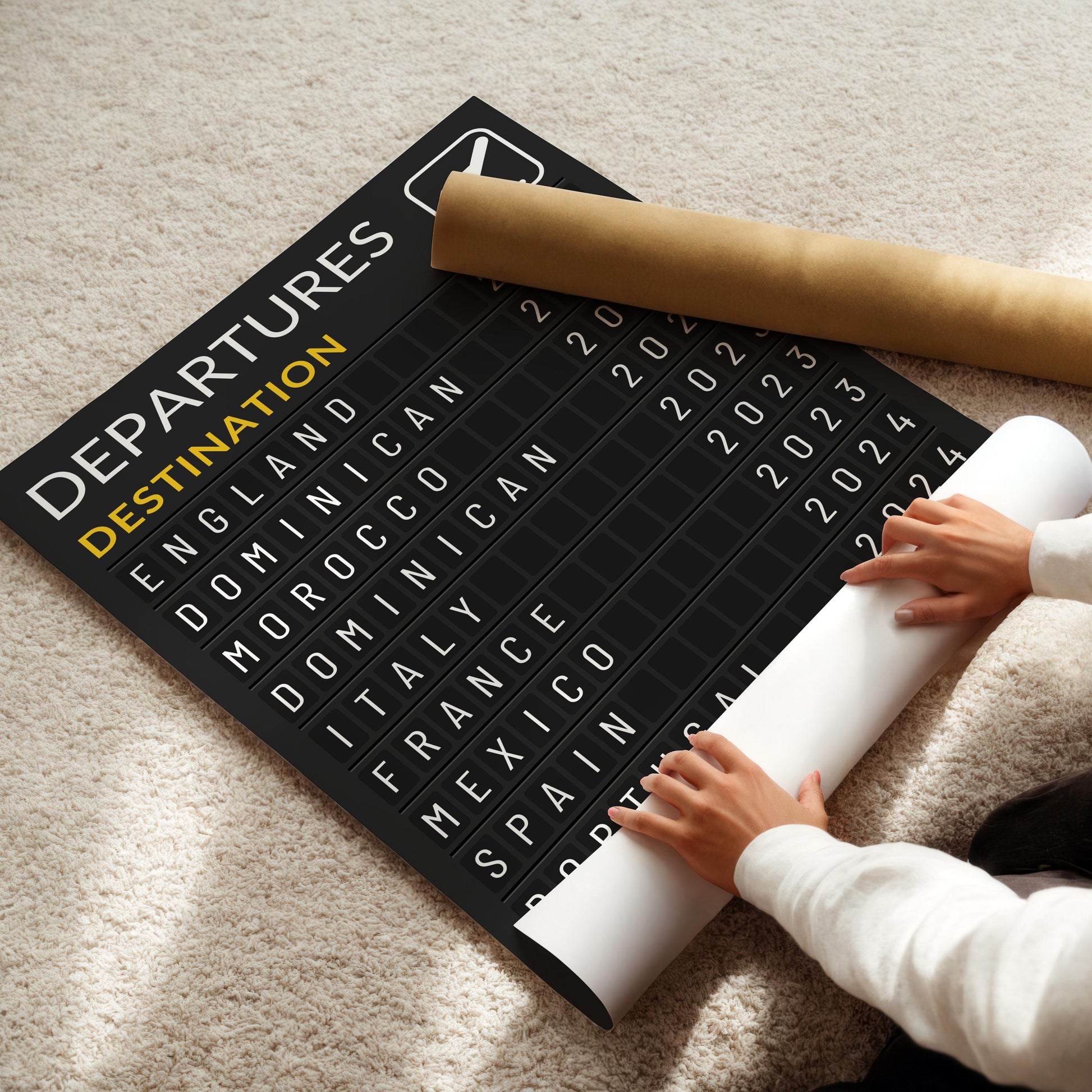 Someone rolling a poster out on a neutral beige carpet. The home decor piece is a personal made item with travel lovers favourite city and beach trips and dates.