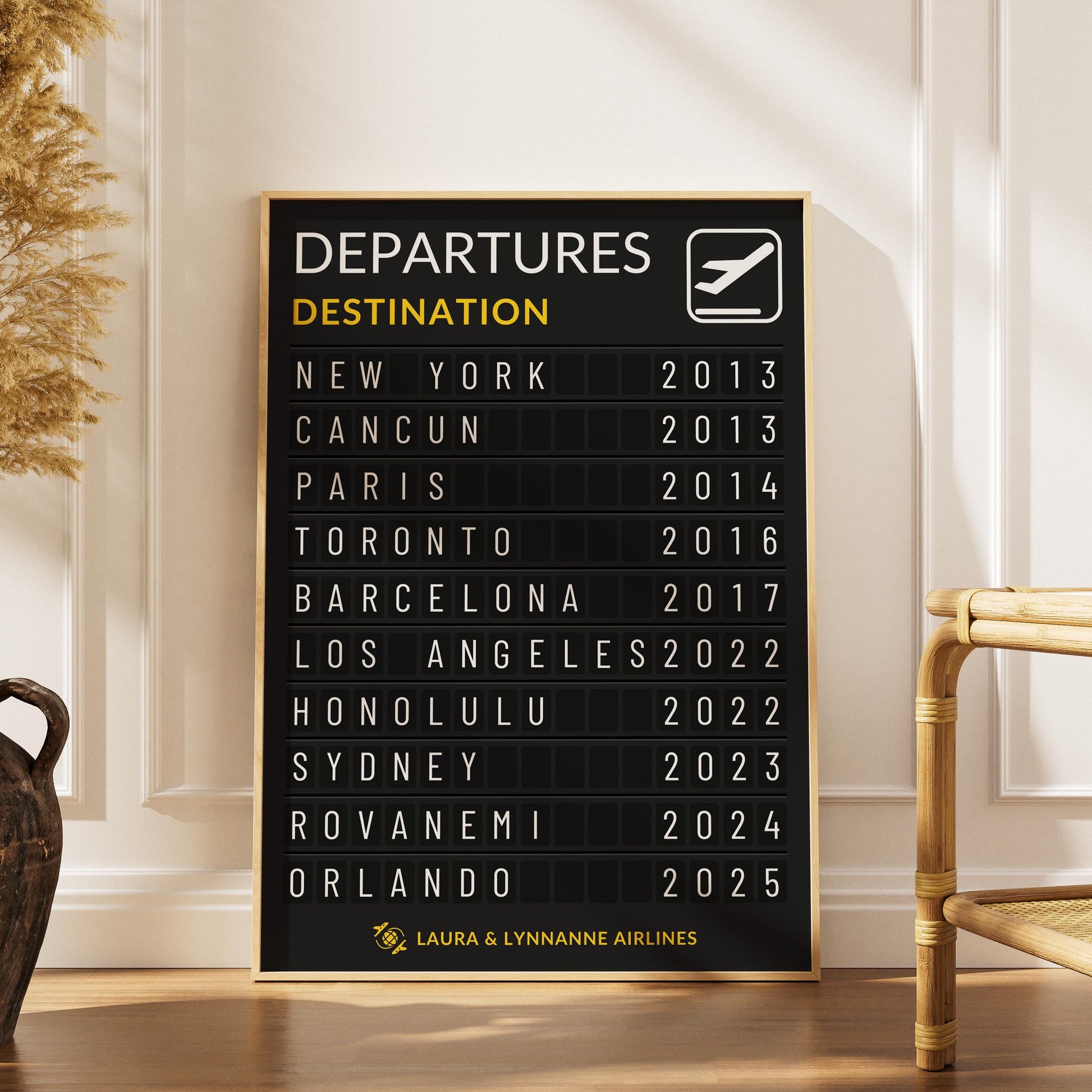 A boho style apartment with a rattan chair and plant next to a wood framed poster of a bespoke made departures information board personal to your travelling memories.