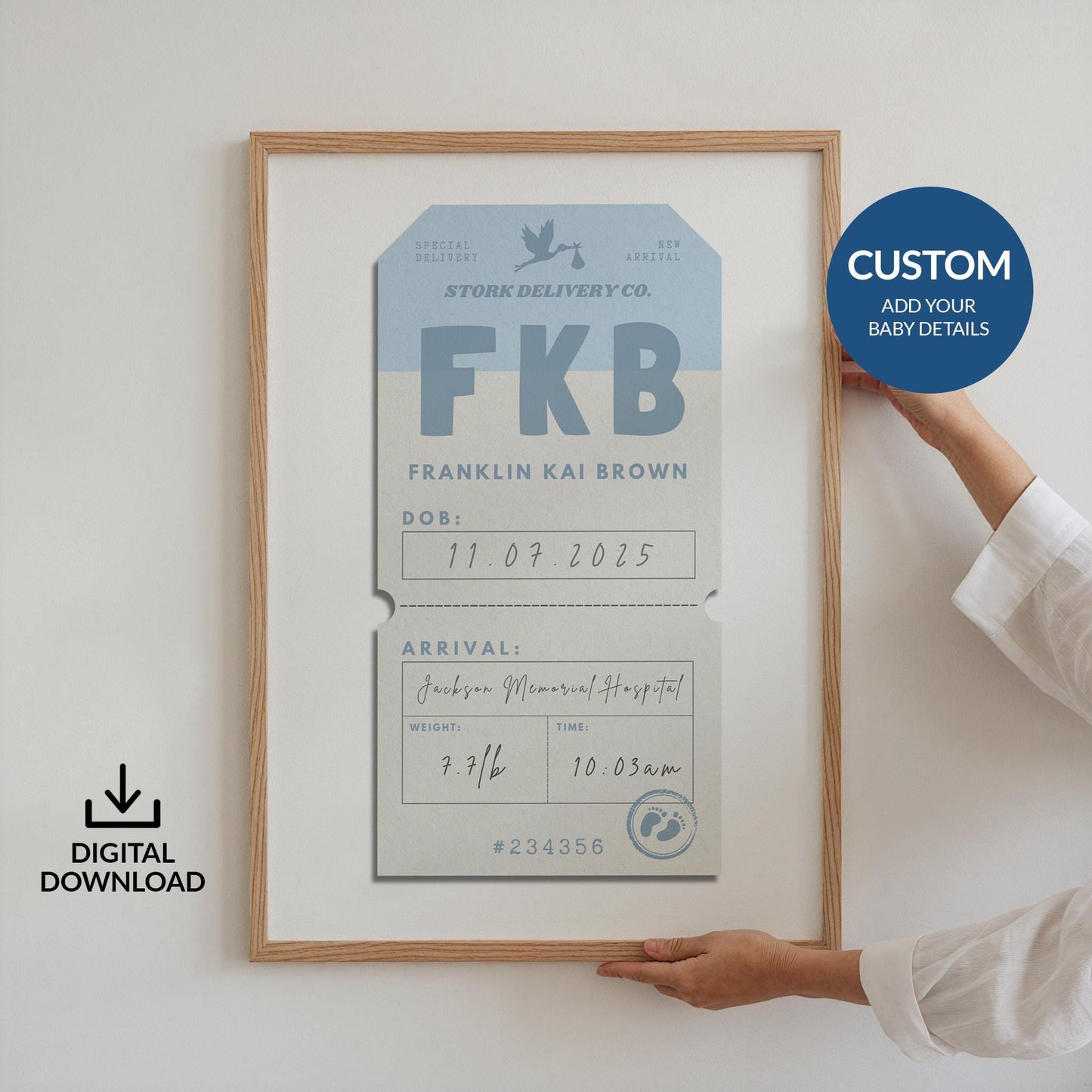 Someone holding up a framed poster against a white wall. The art is a blue vintage luggage tag design with baby arrival details on it such as name, weight and time of birth.