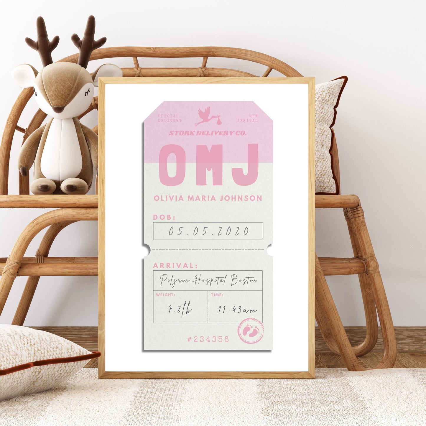 A Livingroom with a rattan bench and children's toys with a poster in a wood frame leaning on the chair. The art is a childs luggage tag with their birth information. It is a quirky keepsake for new parents who love travel.