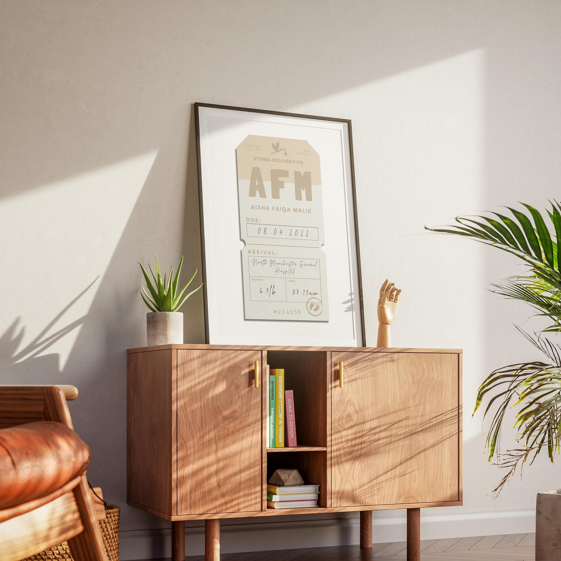 A mid century modern apartment with a wood cabinet which has a black framed poster on top. The art shows a baby boy or girl personalised details from arrival at the hospital.