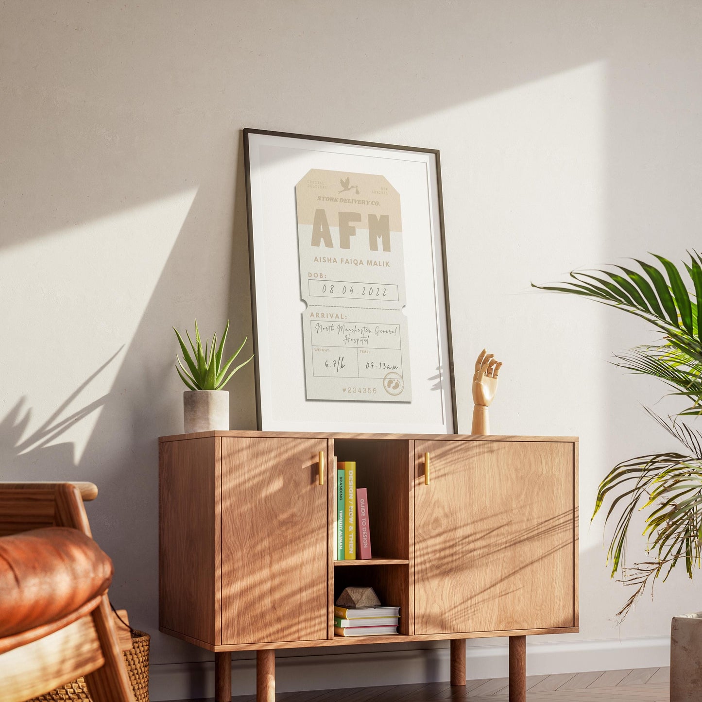 A mid century modern apartment with a wood cabinet which has a black framed poster on top. The art shows a baby boy or girl personalised details from arrival at the hospital.