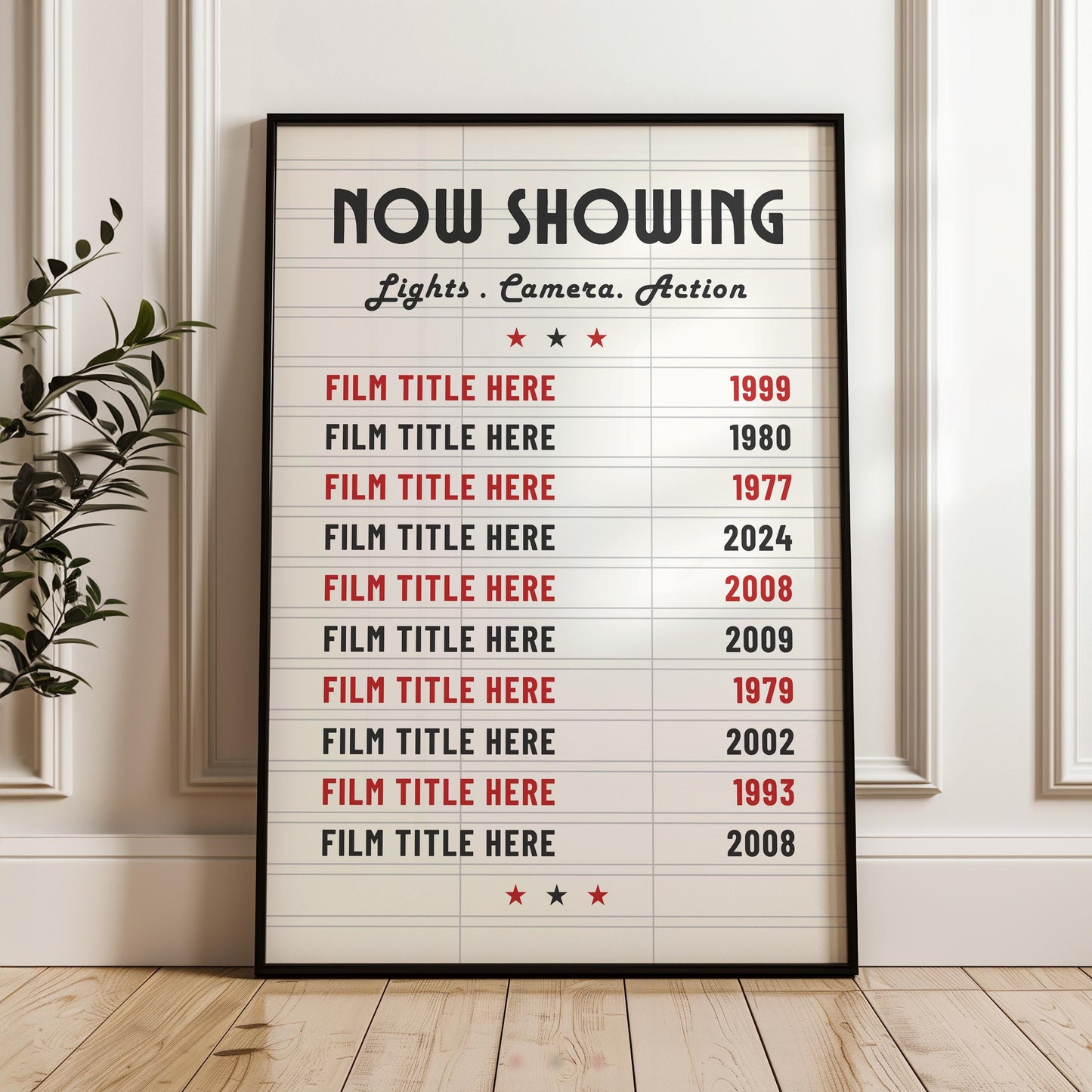 A white panelled wall background with a print in a black frame leaning on the wall. The print is a marquee movie theatre board style with bespoke film choices and their release dates on it.