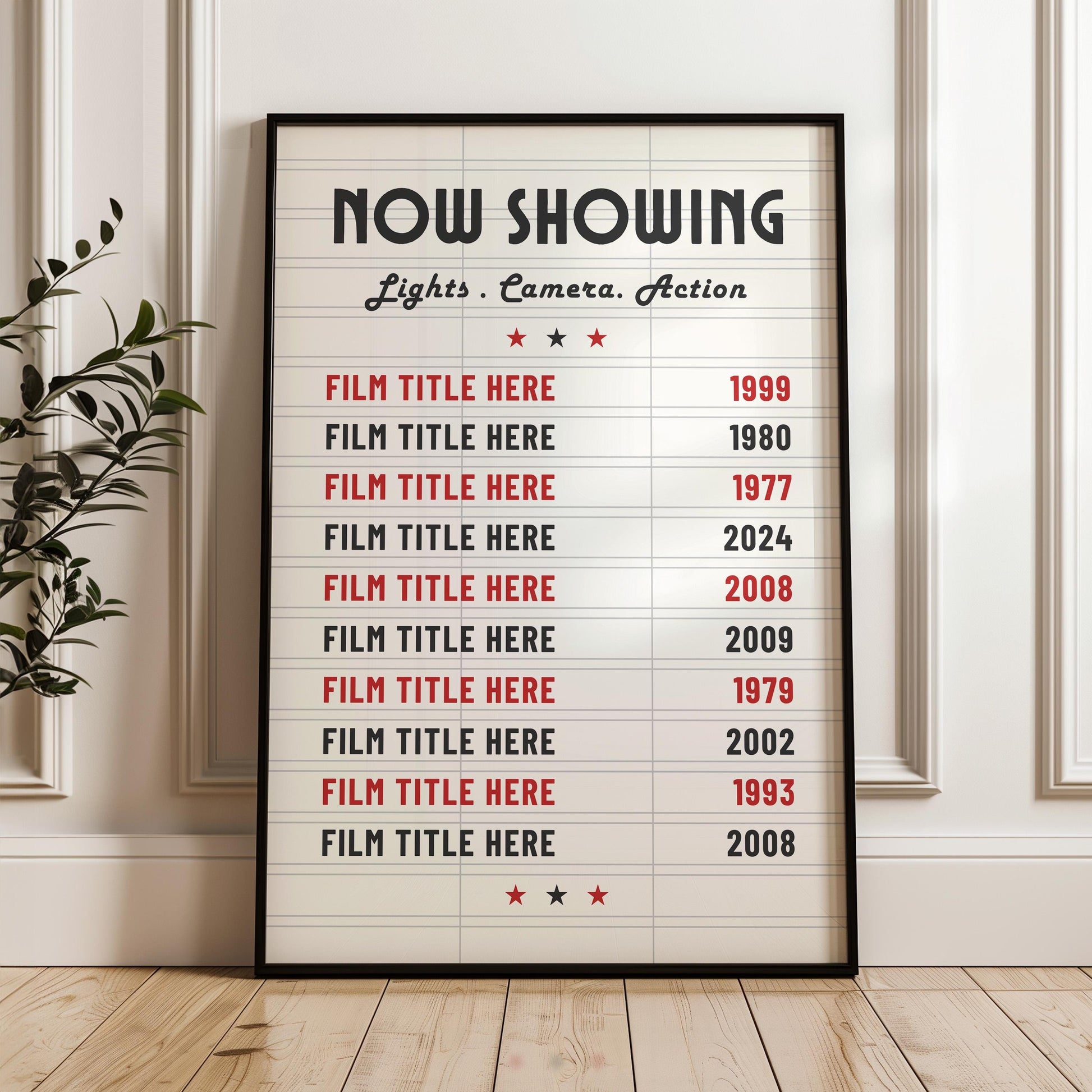 A white panelled wall background with a print in a black frame leaning on the wall. The print is a marquee movie theatre board style with bespoke film choices and their release dates on it.
