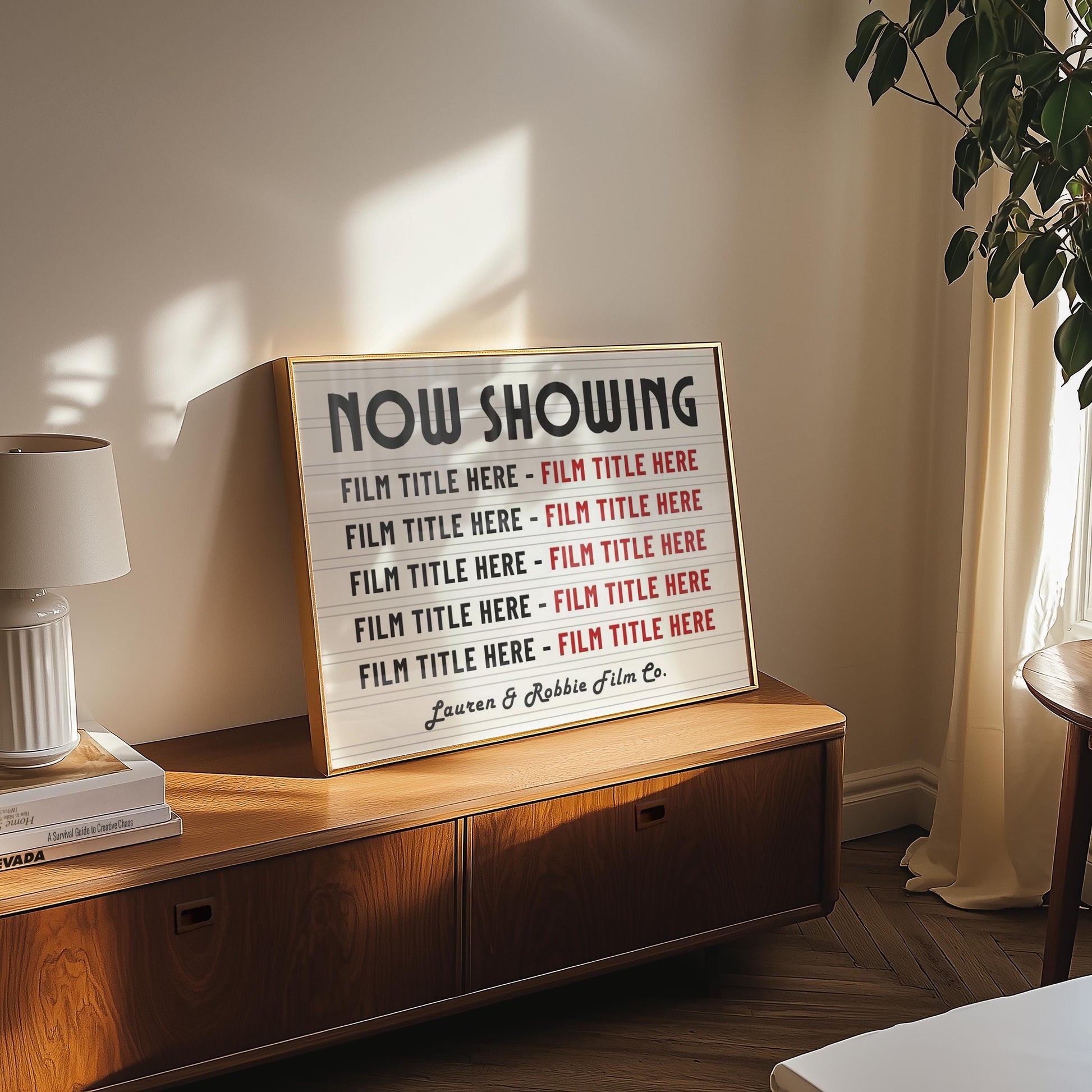 A cosy bedroom with a wood sideboard featuring a bespoke poster. The art is a lightbox movie theatre concept to feature your favourite family, horror old classics or kids films. A title below says "Lauren & Robbie Film Co."