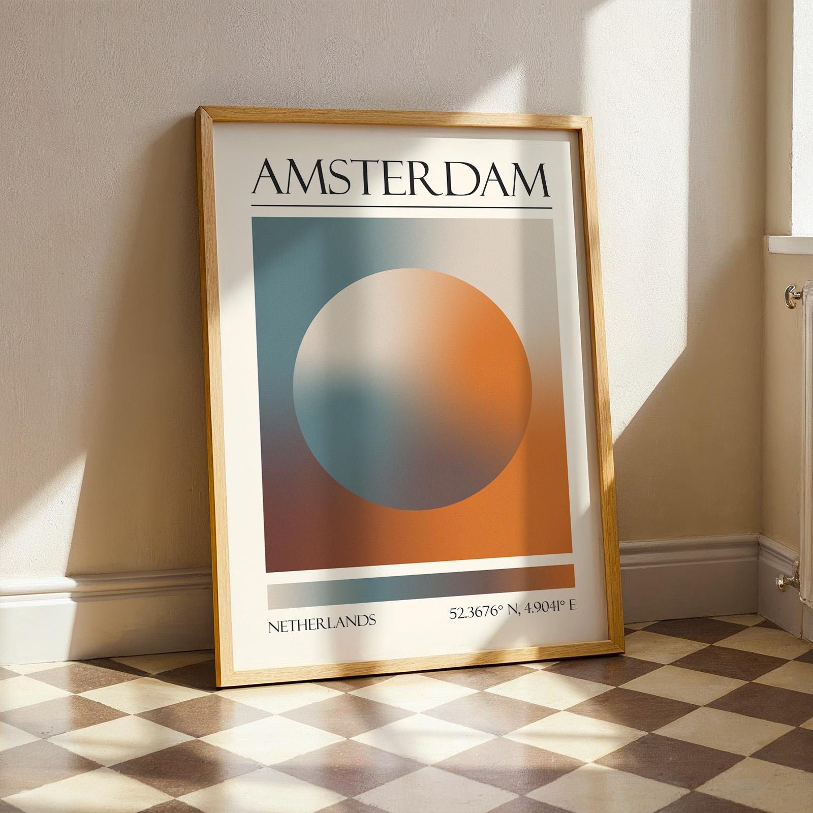 A framed print with the word "AMSTERDAM" at the top. The modern location artwork features orange and teal in an abstract style as colours of Amsterdam. The bottom of the print reads "NETHERLANDS" and includes coordinates.