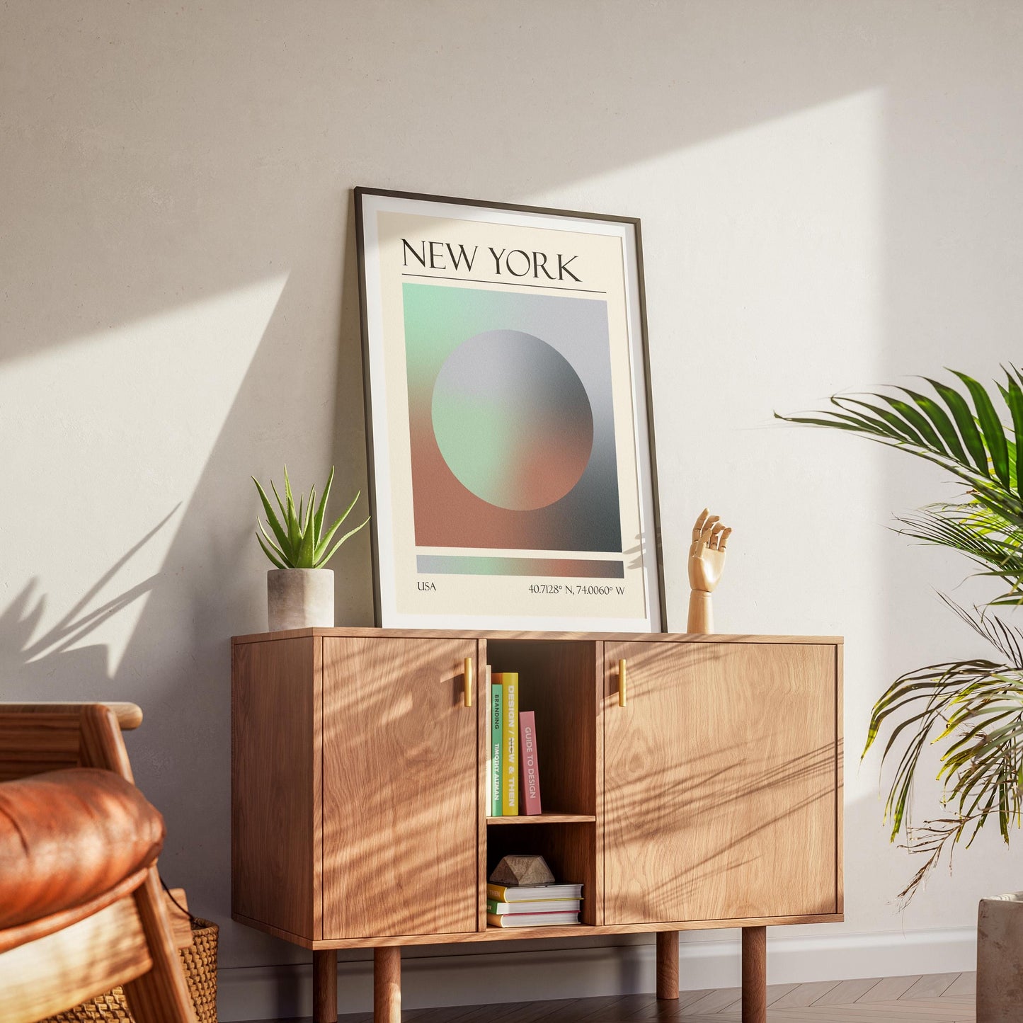 A black frame with an aura gradient circle print inside. The word "NEW YORK" and coordinates are at the bottom. The memory keepsake print is displayed on a wooden cabinet with gold handles.