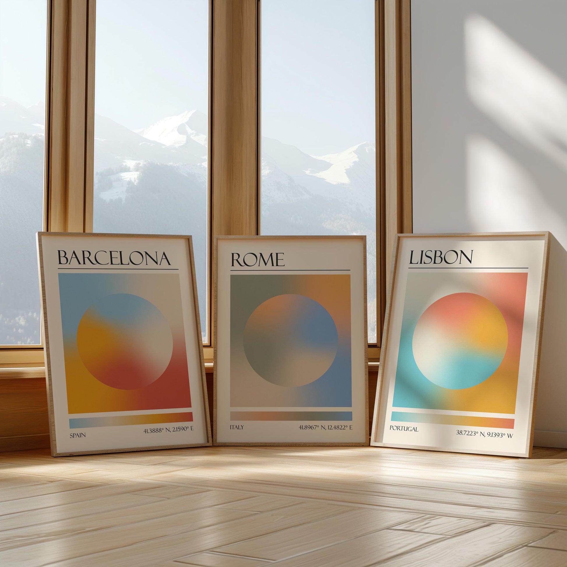 Three framed art prints with abstract designs and gradient colour palettes. The set of three triptych prints each display a city name: Rome, Barcelona, and Lisbon. The prints are in neutral-toned wooden frames, leaning against a window.