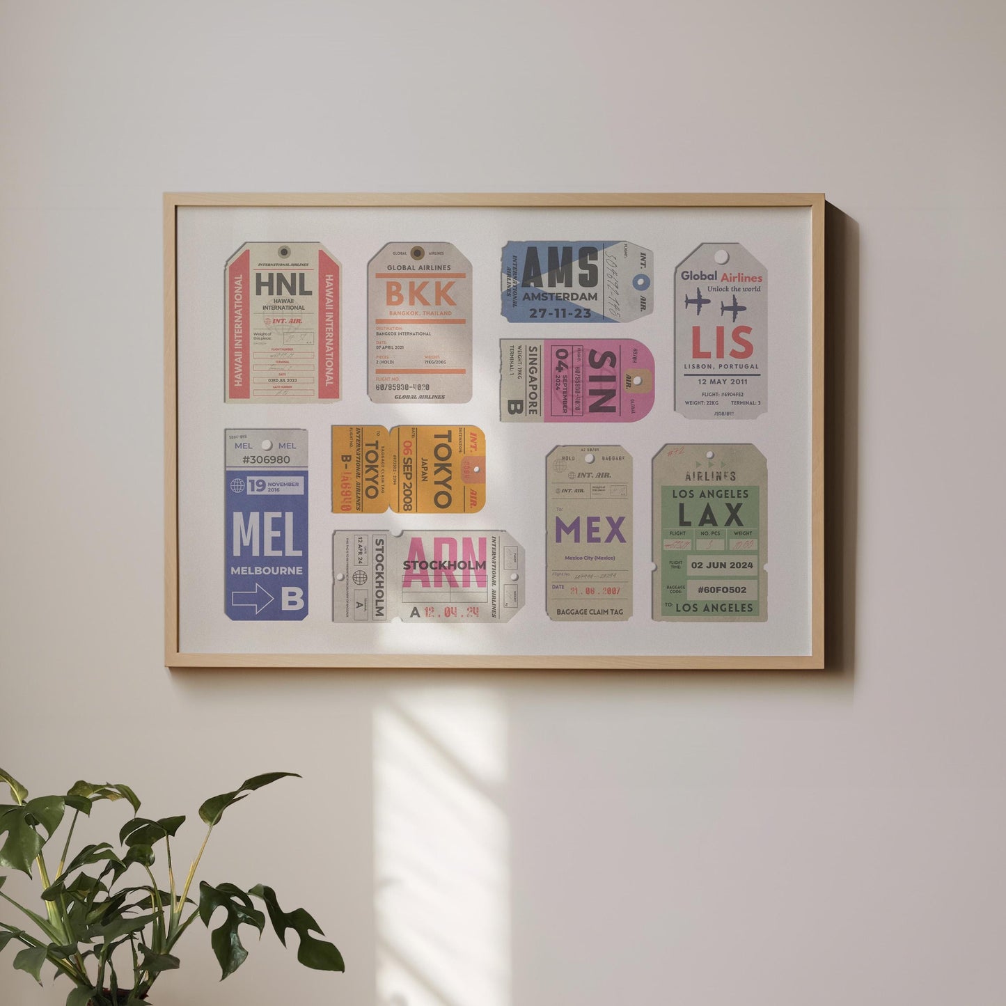 A landscape framed art print hung on a white wall. The poster has vintage luggage tickets on it in colourful schemes showing unique travel places with dates and airport codes.