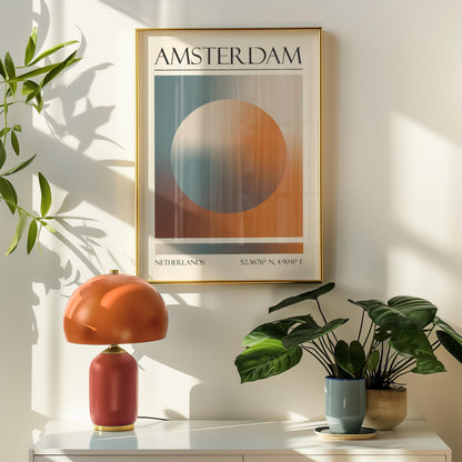 A framed travel poster featuring a geometric aura inspired design in shades of blue, orange, and brown hangs above a orange table lamp. Potted plants are on the right.