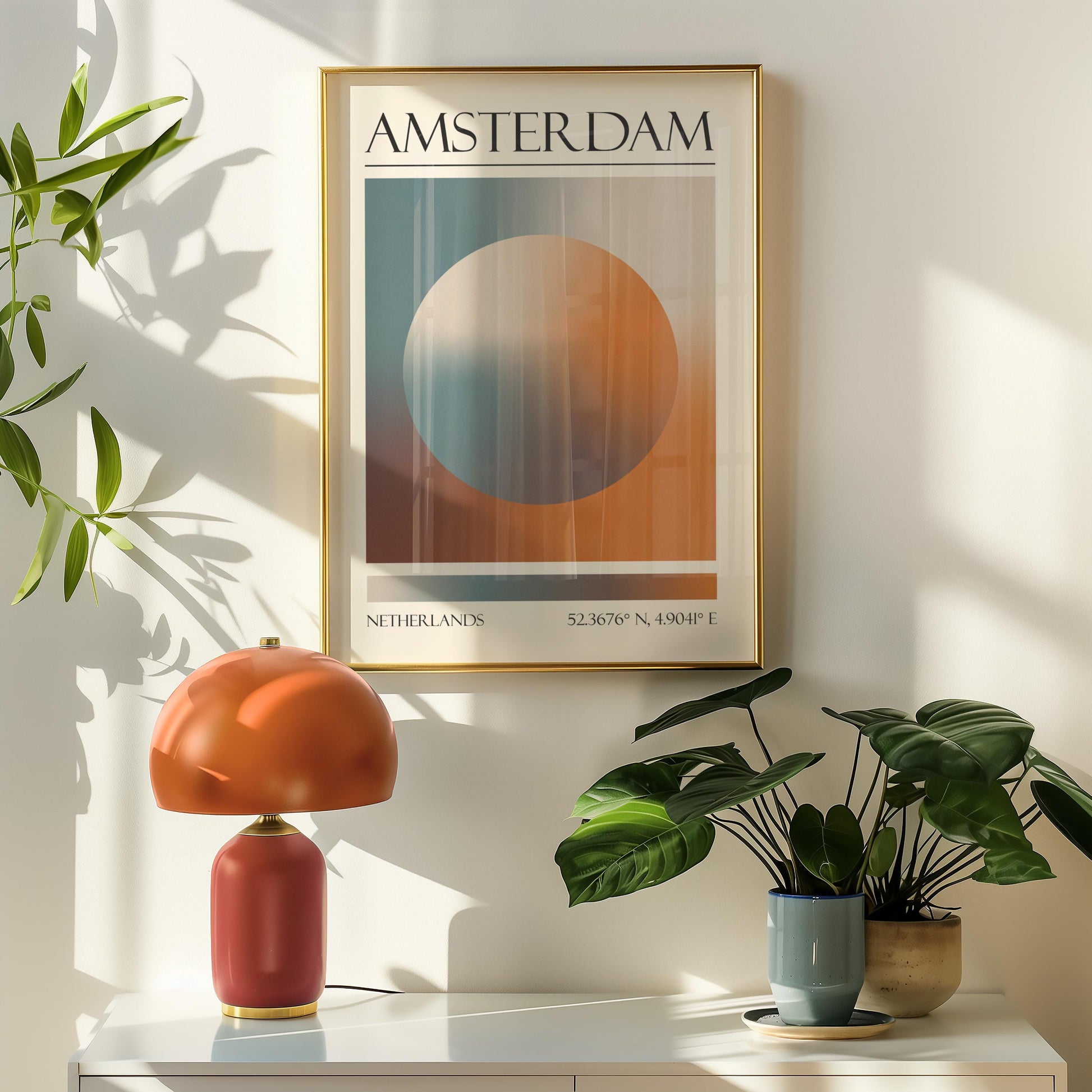 A framed travel poster featuring a geometric aura inspired design in shades of blue, orange, and brown hangs above a orange table lamp. Potted plants are on the right.