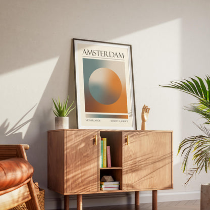 A black frame with an aura gradient circle print inside. The word "NETHERLANDS" and coordinates are at the bottom. The memory keepsake print is displayed on a wooden cabinet with gold handles.