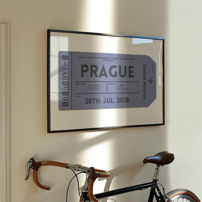 A Parisian flat hallway with a bike leaning on the wall and a framed print hung on the wall. The art is a personalised keepsake of a luggage tag with custom details on it