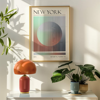 A framed travel poster featuring a geometric aura inspired design in shades of grey, green, and pink hangs above a orange table lamp. Potted plants are on the right.