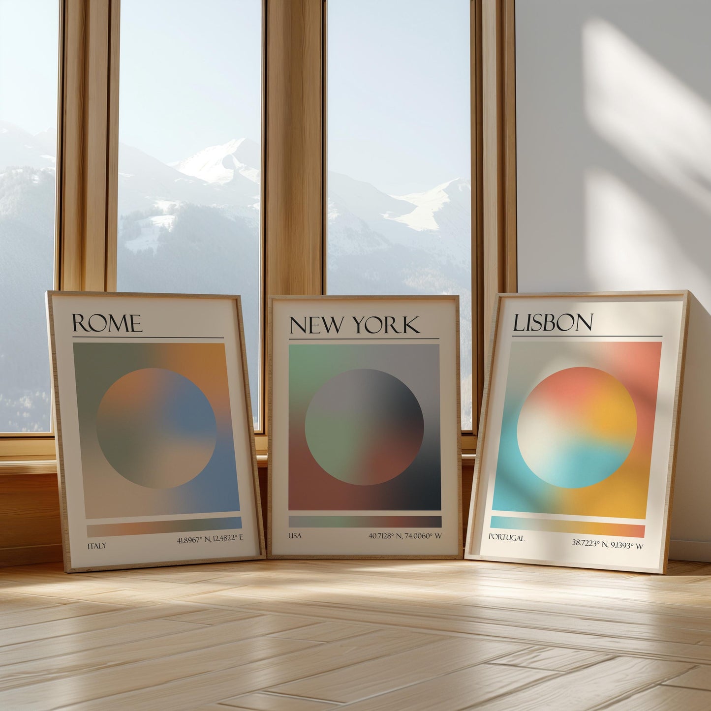 Three framed art prints with abstract designs and gradient colour palettes. The set of three triptych prints each display a city name: Rome, New York, and Lisbon. The prints are in neutral-toned wooden frames, leaning against a window.