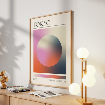 A framed print with the word "TOKYO" at the top. The destination artwork features a colourful aura circle in pink, orange and black. A gold lamp with four white globe lights is to the right in the hallway.
