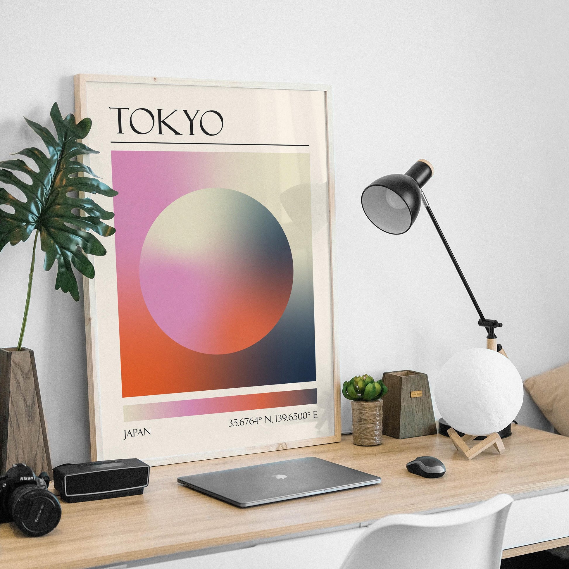 An abstract print is on a wooden desk, with a black desk lamp and a moon-shaped light in a masculine home office. The art gives a zen modern aesthetic.