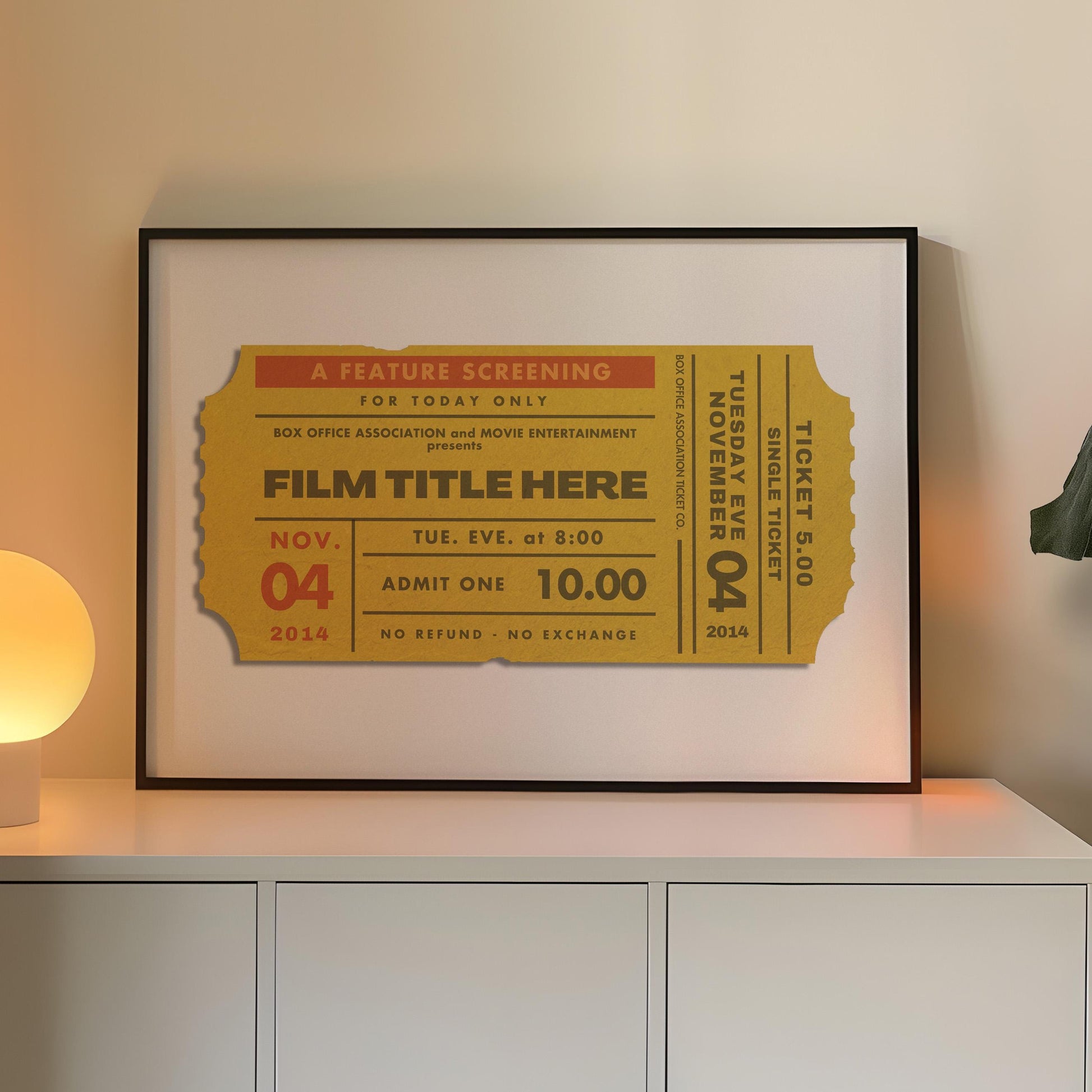 A cosy Livingroom with warm lighting and a large horizontal frame leaning on the wall. The art is minimalist and bespoke made inspired by old movie theatre tickets