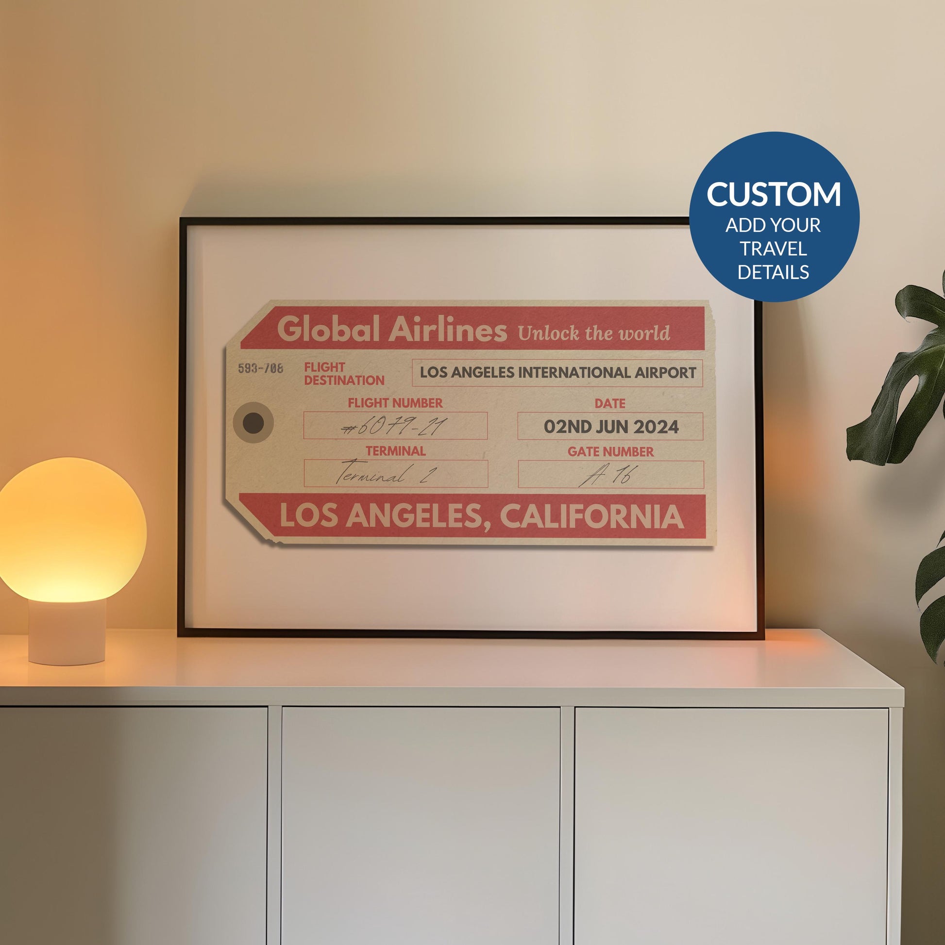 A cosy bedroom with a white chest of draws and plant. A poster is in a black frame near a lamp showing an old luggage tag design which has been made bespoke with personalised text.