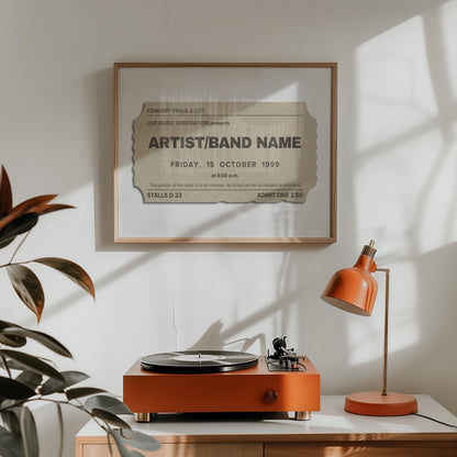 A record player and retro orange lamp are on a ounter with a landscape wall decor in an oak frame hung above. The bespoke poster shows a ticket stub for a live music event. It has a custom title, date venue, city and seat number.