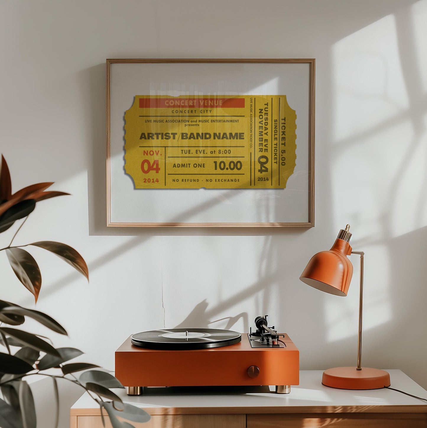 A record player and retro orange lamp are on a counter with a landscape wall decor in an oak frame hung above. The bespoke poster shows a ticket stub for a live music event. It has a custom title, date venue, city and seat number.