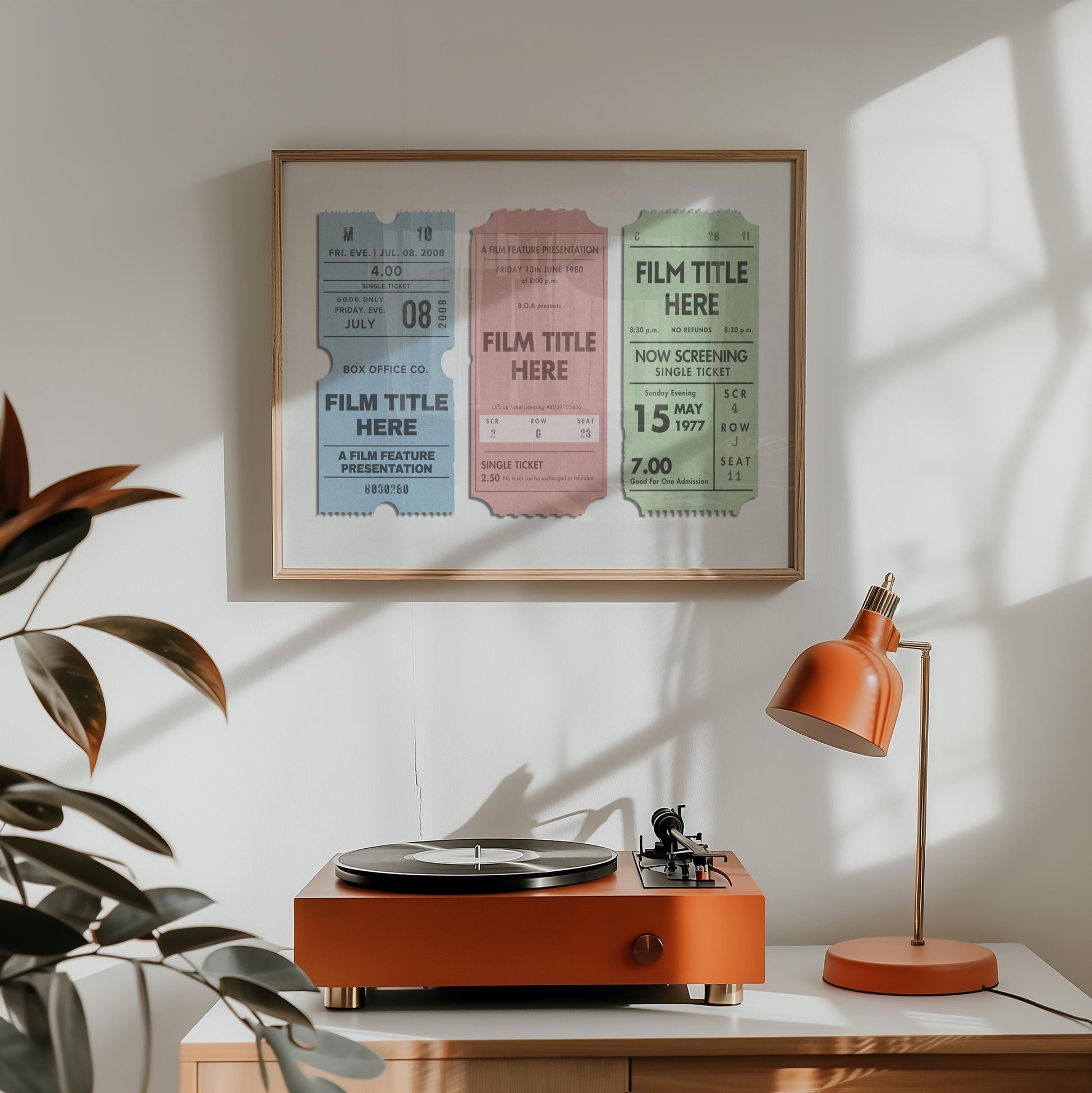 A retro style home living room with a record player and orange lamp. The landscape art on the wall shows three movie theatre tickets with personalised film titles and dates on them.