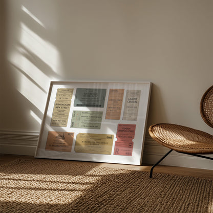 A muted tone of colour art print showing retro railway tags with custom details and destinations on them. The art is leaning on the wall in a boho style living room with a rattan rug and chair.