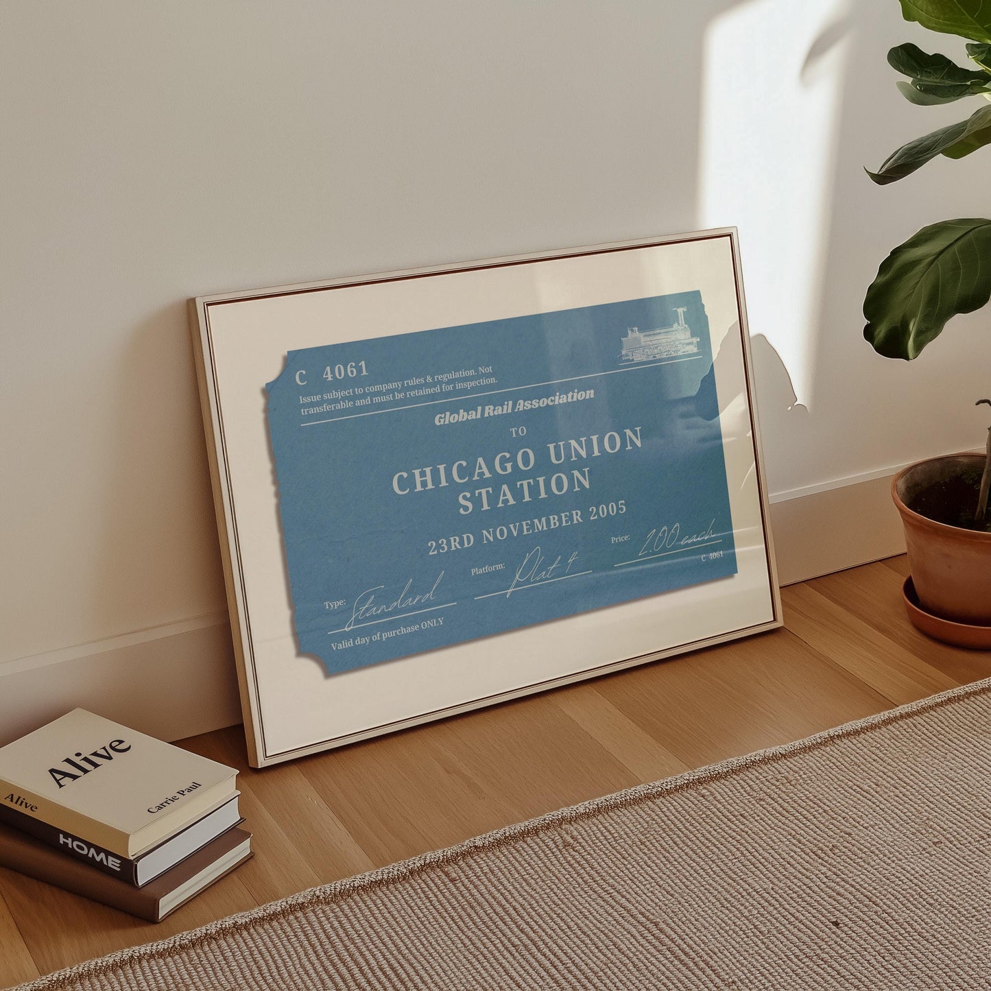 A minimalist apartment hallway with books and a poster on the floor. The print is a travel keepsake with a bespoke vintage rail luggage tag made as a trendy holiday memory décor piece.