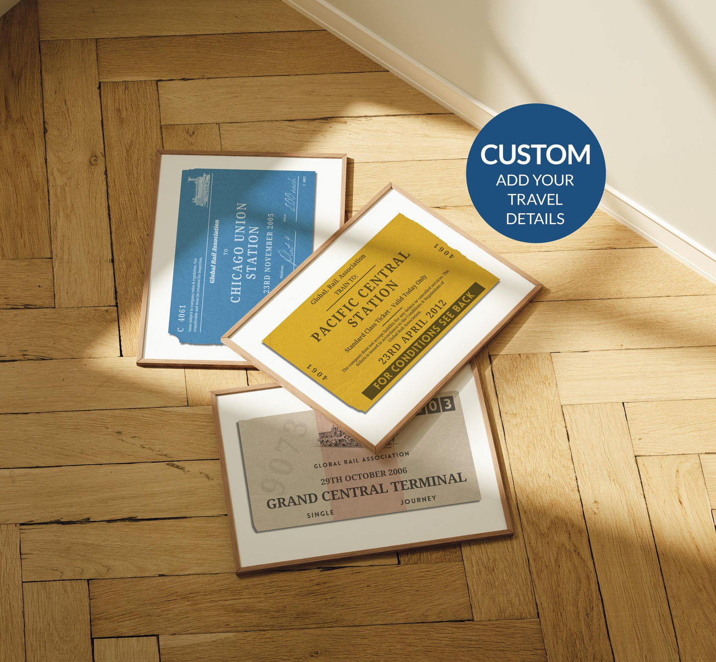 A rustic wood parquet floor with three framed prints laid out on the floor. One is a vintage yellow, blue and the other beige. All are made to look like old train station tickets you would find and collect from travelling.