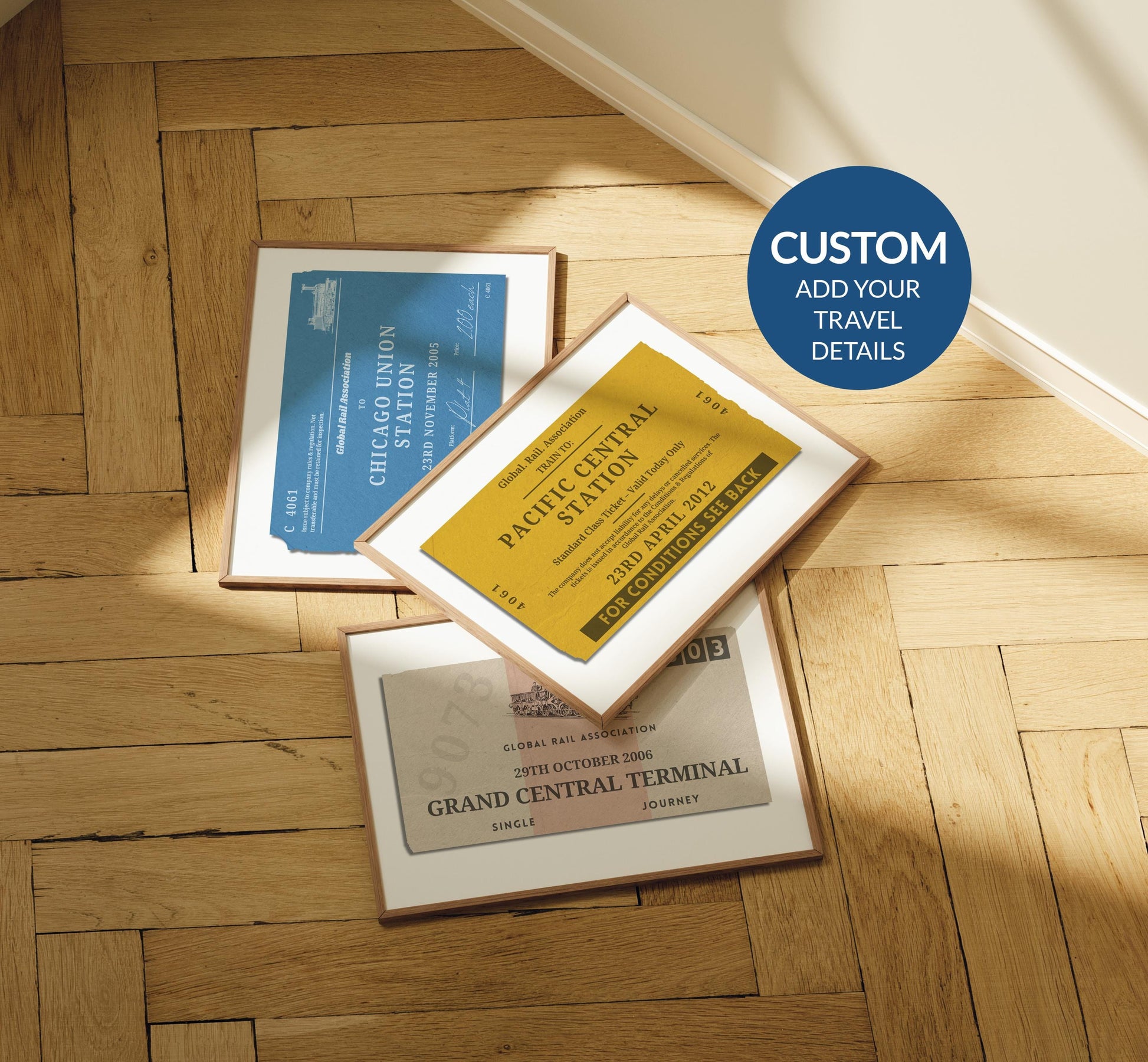 A rustic wood parquet floor with three framed prints laid out on the floor. One is a vintage yellow, blue and the other beige. All are made to look like old train station tickets you would find and collect from travelling.