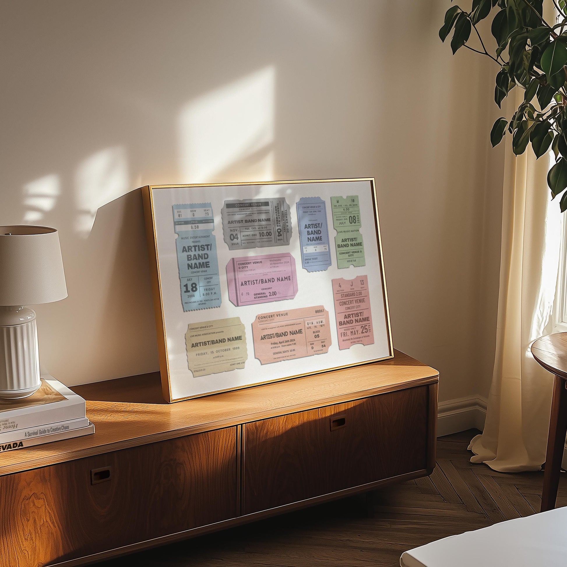 A cosy bedroom with a wood draw unit and a lamp above. Art is leaning on the wall which has colourful festival ticket passes on it with bespoke text. It is a custom made music lover design.
