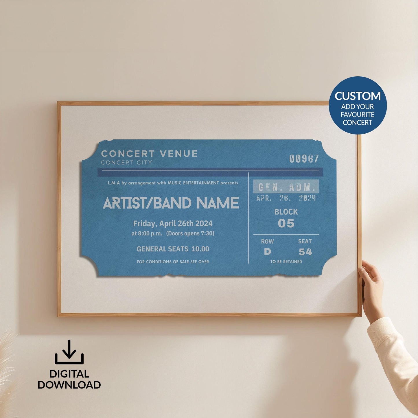 Someone in a white top holding up a large horizontal print on the wall. The art is of a vintage concert ticket stub with personalised text on it.