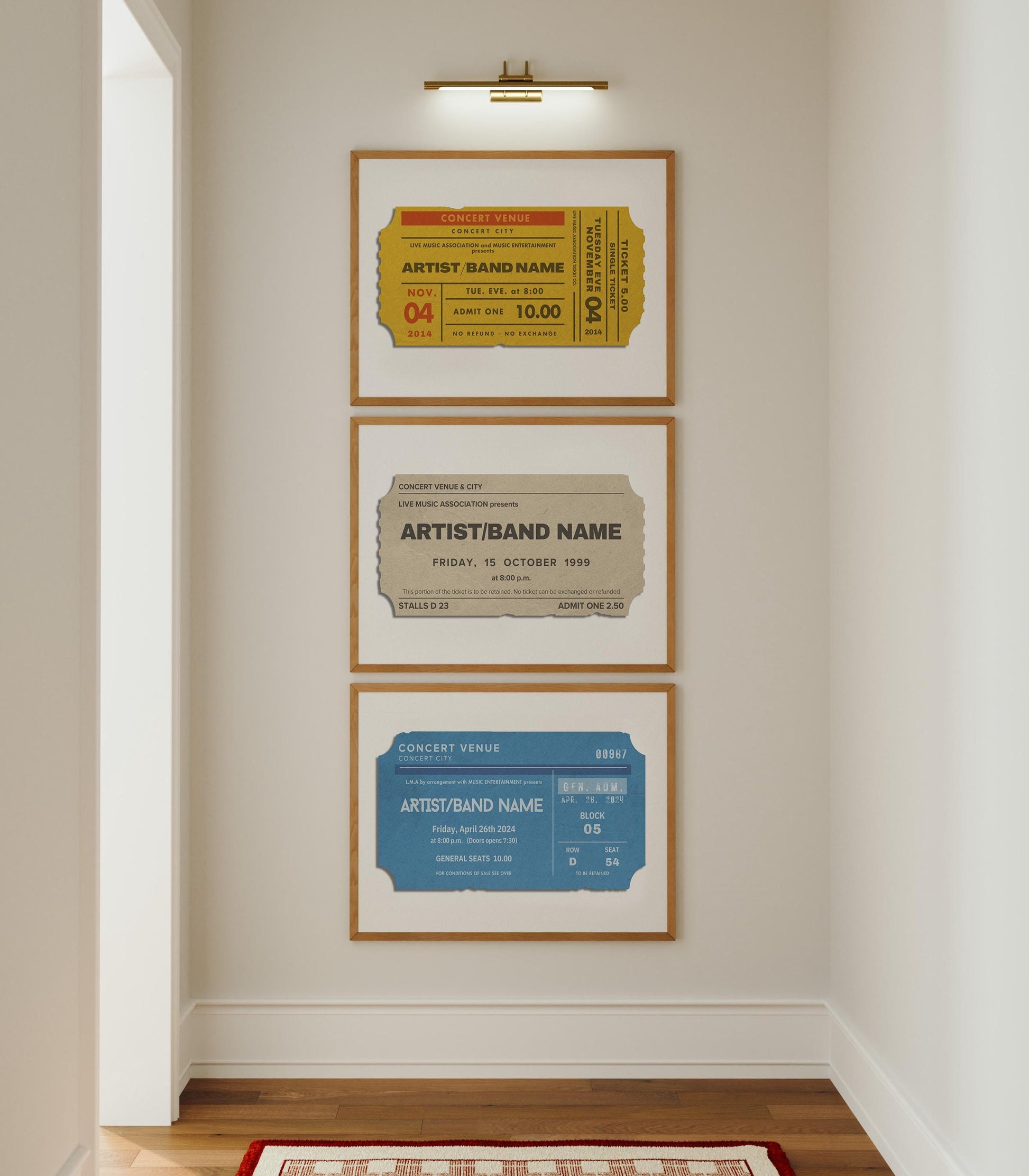 A white hallway with a set of three tryptich home decor prints on the wall under a gallery light. A yellow, blue and beige concert ticket stub is on each with bespoke artist names and details from past events.